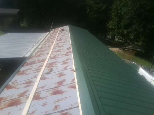 Old rusted panels beside newly installed green metal roofing — Wind Damage Roof Repair by Roofing Brothers in Weedsport