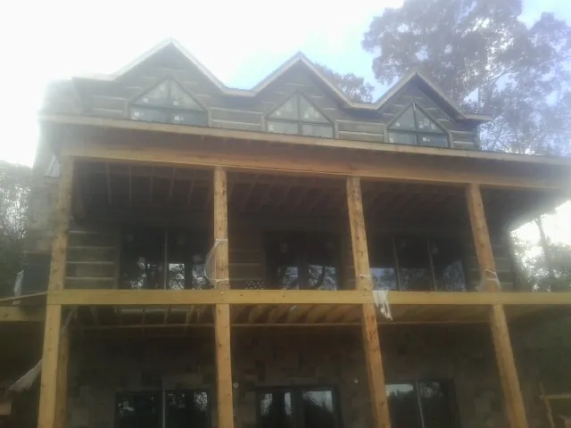 Dormers and porch framing on a large log home under construction — Roof Coating work by our crew in Weedsport