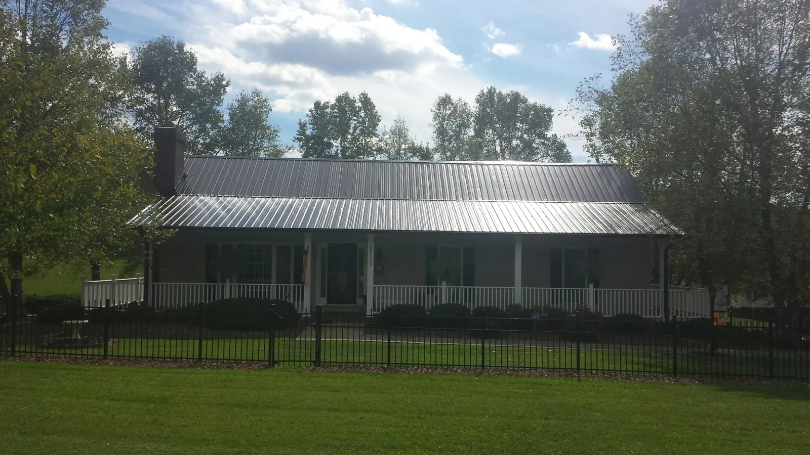 Gray metal roof on a brick ranch with a full width front porch — Gutter Guard Installation work by our crew in Weedsport
