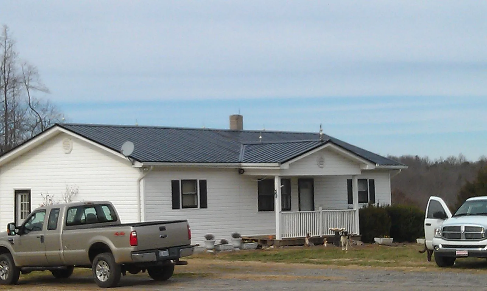 Finished dark metal roof on a white ranch home with work trucks parked in Weedsport