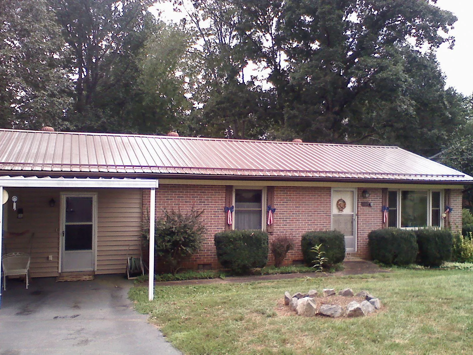 Bronze metal roof and carport on a brick ranch home — Roof Repair work by our crew in Weedsport