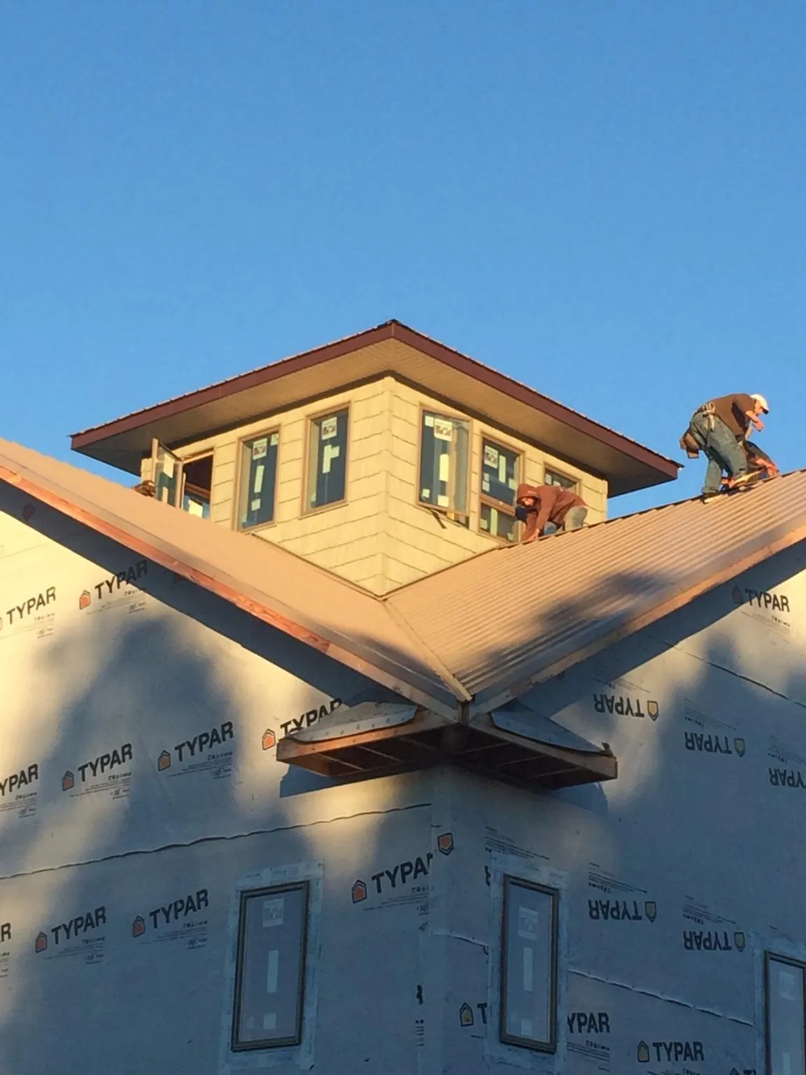 Roofers working around a rooftop cupola on a new metal roof at sunset — Roof Waterproofing in Weedsport by Roofing Brothers